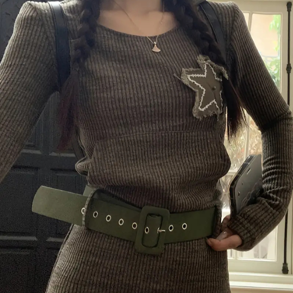 Vrouw in geribbelde bruine jurk met sterapplicatie, groene riem en vlechten. Modieuze herfstoutfit, casual dameskleding, trendy stijl.