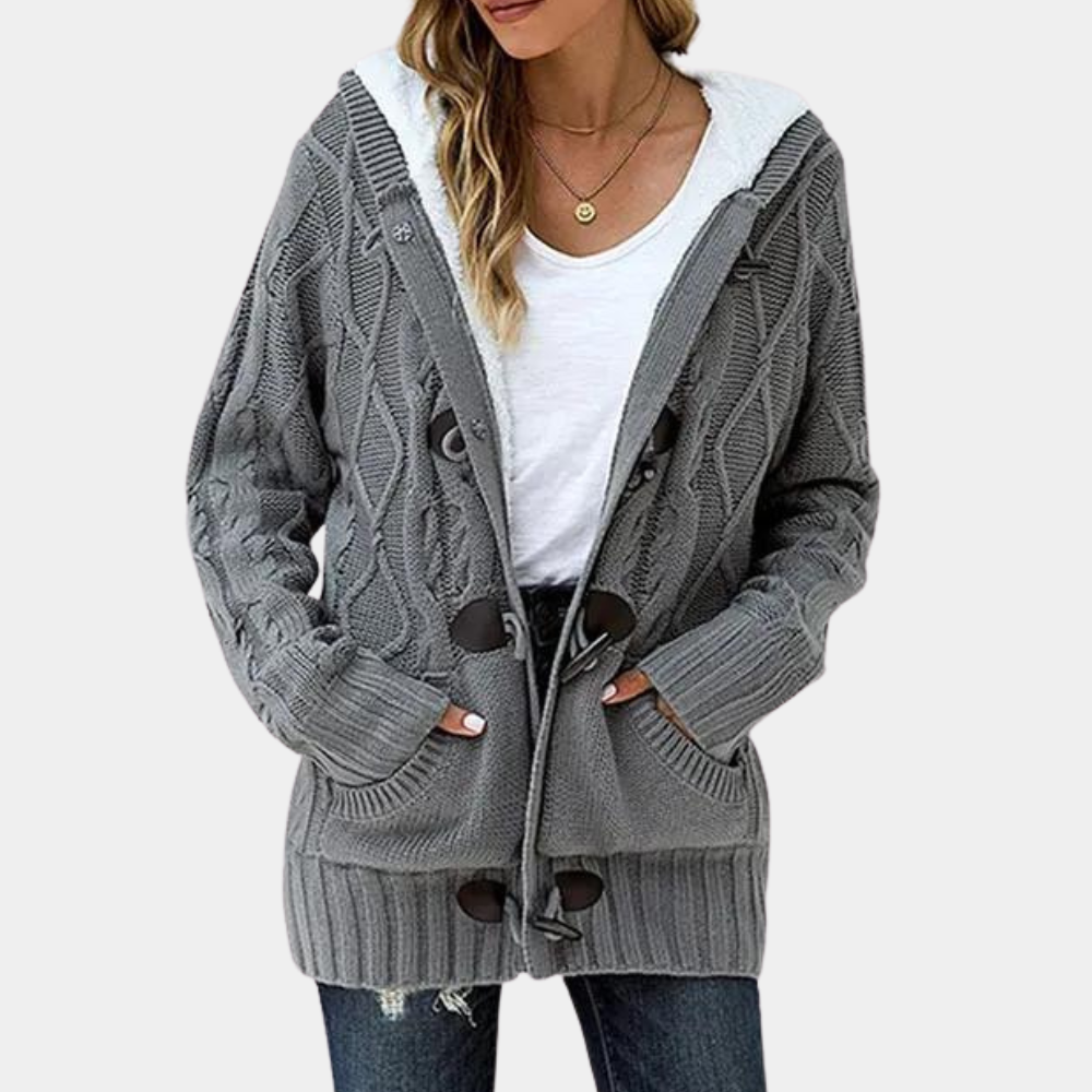 Grijze gebreide damesvest met capuchon, knopen en zakken, gedragen over een wit T-shirt en jeans. Comfortabele herfstmode, casual stijl.