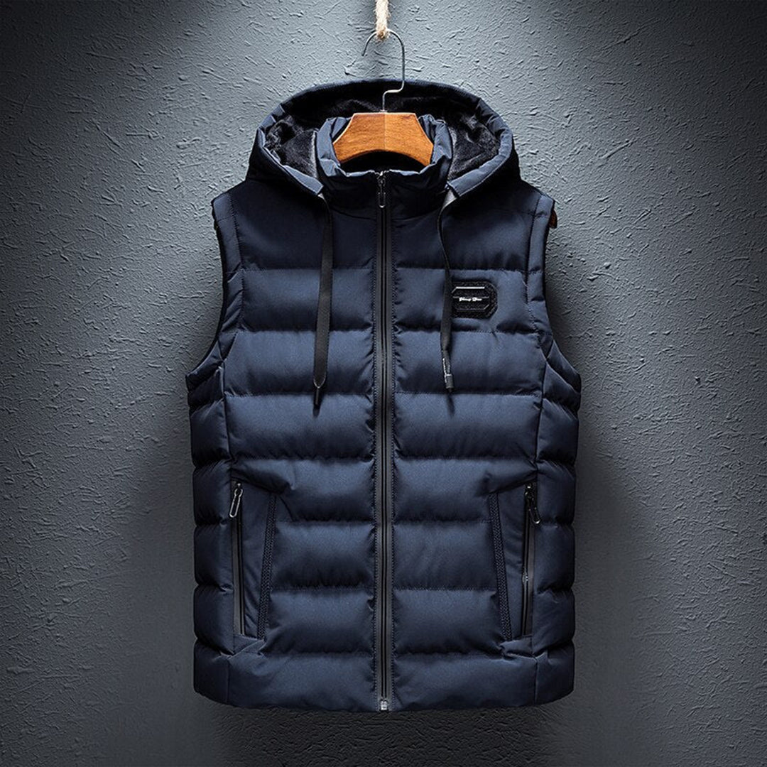 Donkerblauwe heren bodywarmer met capuchon, gewatteerd ontwerp, ritssluiting en zakken. Stijlvolle en warme winterkleding voor heren.