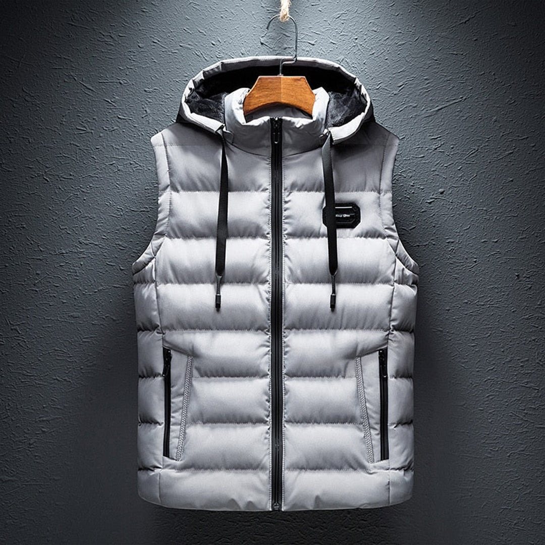 Grijze gewatteerde bodywarmer met capuchon voor heren, ritssluiting en zakken. Stijlvolle herenkleding, wintermode, casual outfit.