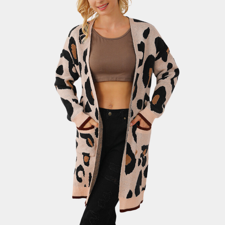 Vrouw draagt lange, beige luipaardprint cardigan met bruine en zwarte accenten, gecombineerd met een bruine crop top en zwarte jeans.