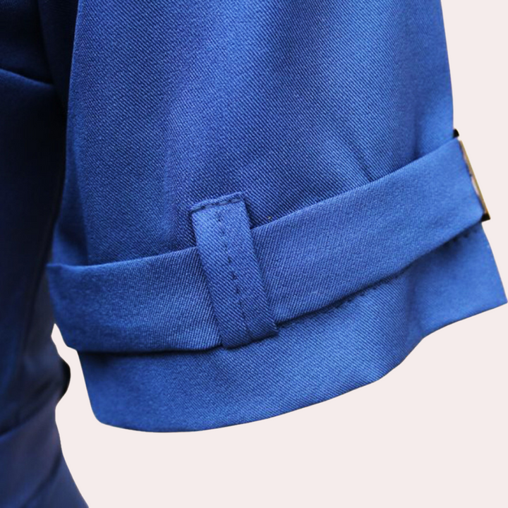 Blauwe damesjumpsuit met V-hals, elegante opgerolde mouw, modieuze kleding, hoogwaardige stof, trendy damesmode, stijlvolle outfit.
