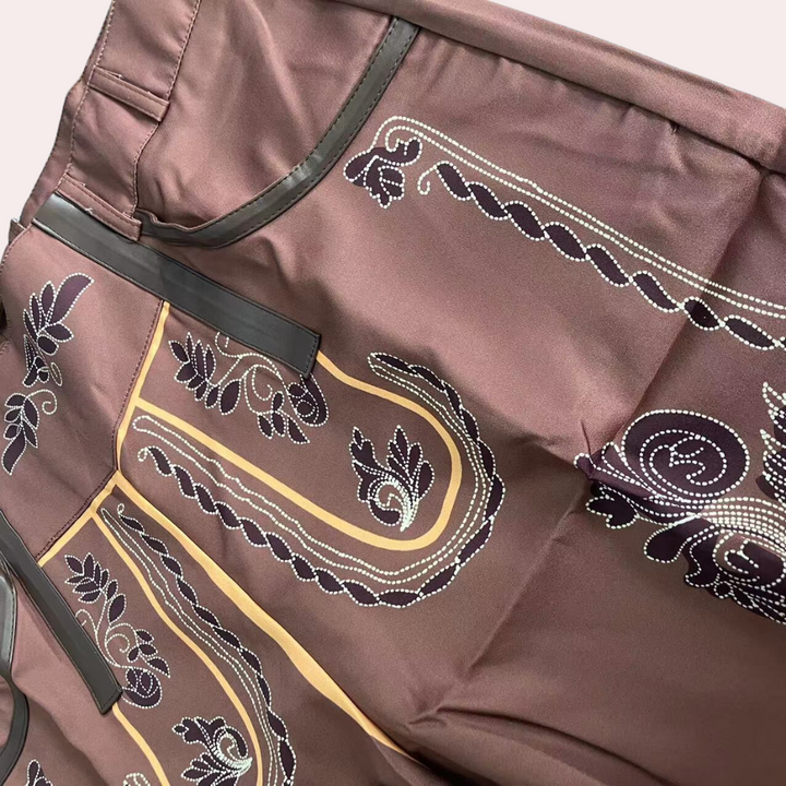 Leren korte broek voor heren in bruin met sierlijke patronen en zwarte accenten. Stijlvolle herenkleding, ideaal voor casual en trendy outfits.