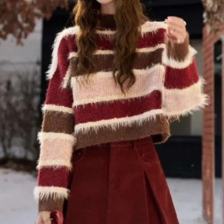 Damestrui met brede horizontale strepen in rood, roze en bruin, gemaakt van pluizige stof. Perfect voor herfstmode en winteroutfits.