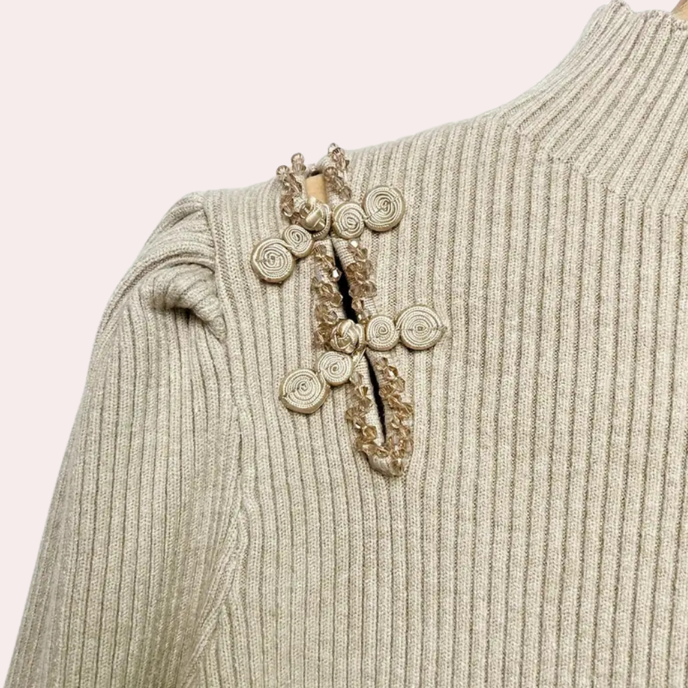 Beige geribbelde trui met decoratieve schouderbroche, gedetailleerd met kralen en spiralen. Modieuze dameskleding, herfst-winter collectie.