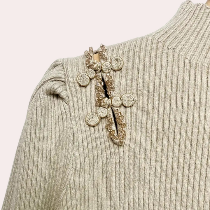 Beige geribbelde trui met decoratieve schouderbroche, gedetailleerd met kralen en spiralen. Modieuze dameskleding, herfst-winter collectie.