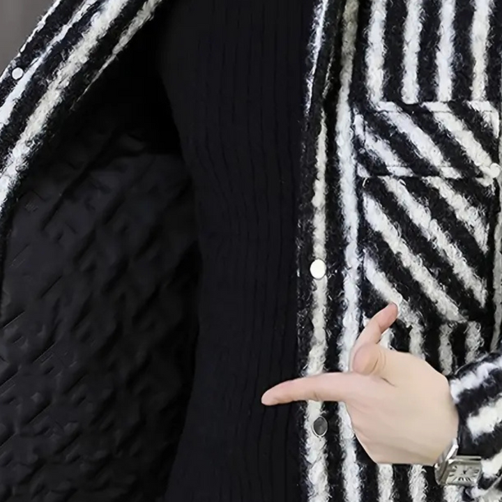 Gestreepte zwart-witte jas met knopen, gedragen door persoon die naar binnenvoering wijst. Modieuze winterkleding, trendy damesjas.