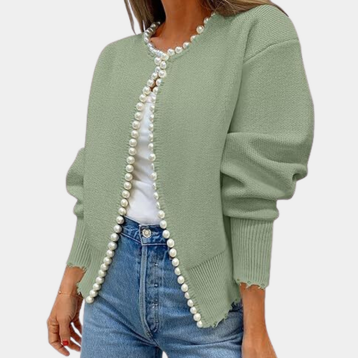 Vrouw in groene gebreide cardigan met parelknopen, witte top en blauwe jeans. Modieuze dameskleding, casual stijl, herfstmode.