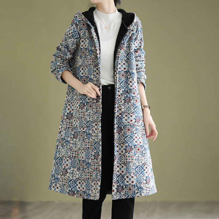 Vrouw draagt lange, kleurrijke winterjas met patroon, capuchon en zwarte voering. Modieuze dameskleding, casual stijl, herfst-winter outfit.