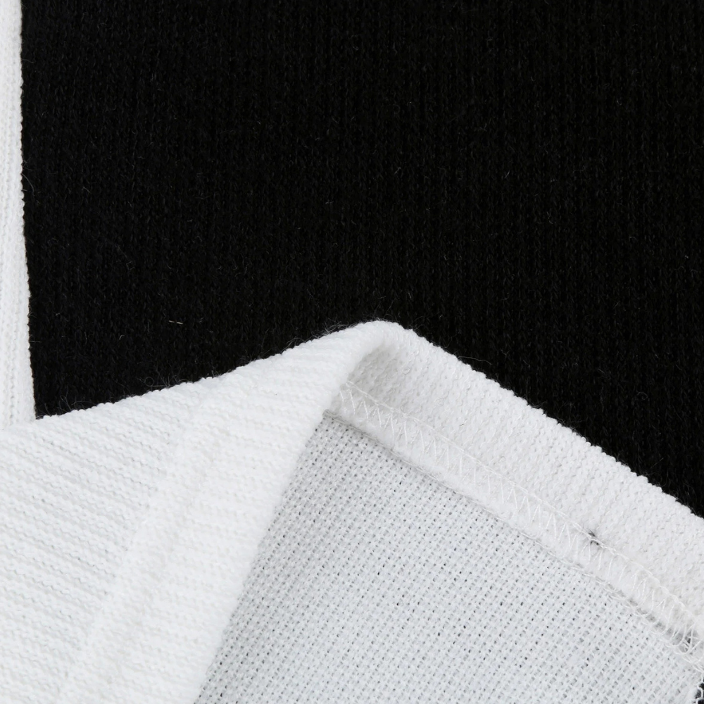 Zwart-witte katoenen stof close-up, textuur en stiksel zichtbaar. Ideaal voor modeontwerp, kledingproductie, hoogwaardige textielmaterialen.