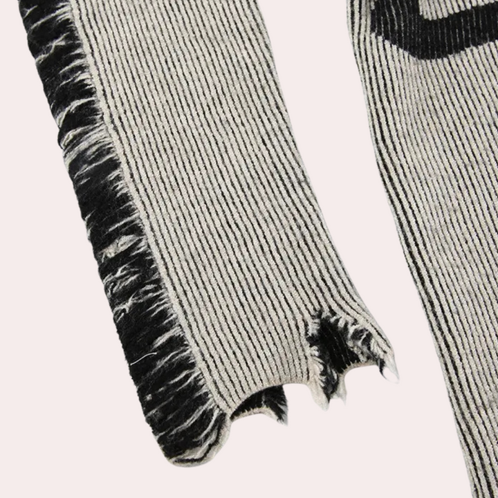 Grijs-zwart gestreepte trui met gerafelde mouwen en asymmetrische zoom, modieuze dameskleding, herfst-winter collectie.