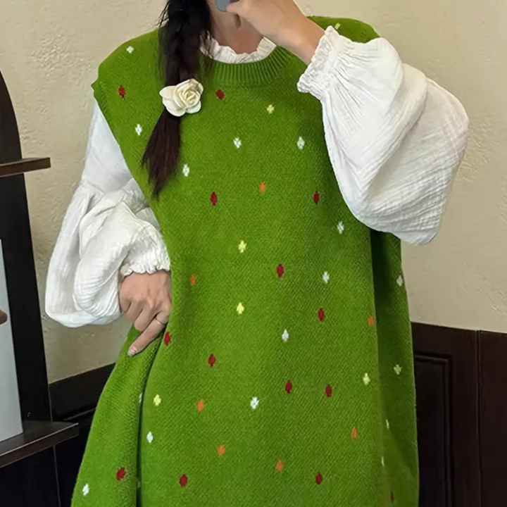 Vrouw draagt groene gebreide trui met kleurrijke stippen en witte blouse. Modieuze herfstkleding, trendy damesmode, comfortabele outfit.