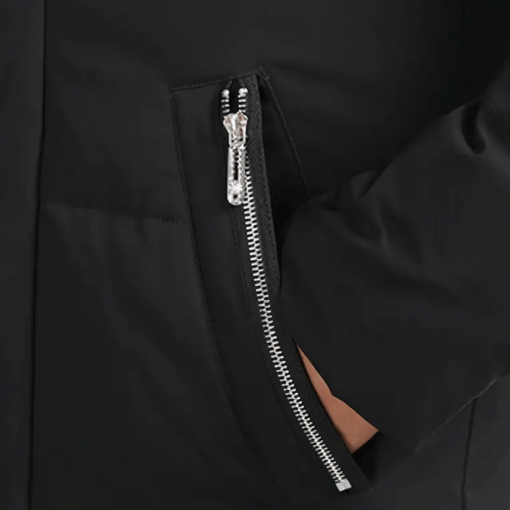 Zwarte jas met zilveren ritssluiting en hand in zak. Modieuze winterjas, hoogwaardige stof, stijlvolle en functionele buitenkleding.