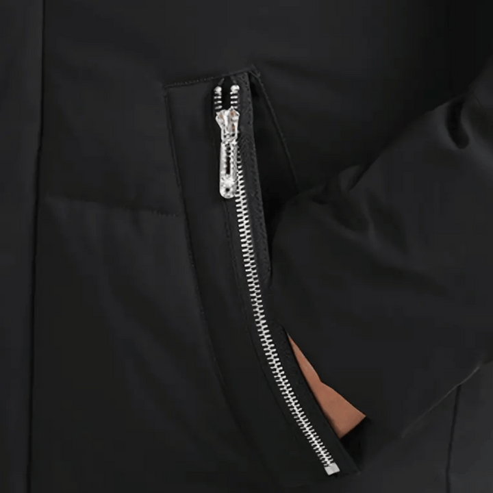 Zwarte jas met zilveren ritssluiting en hand in zak. Modieuze winterjas, hoogwaardige stof, stijlvolle en functionele buitenkleding.