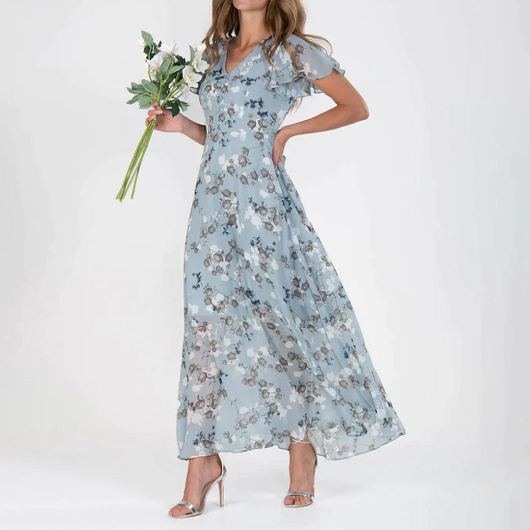 Vrouw in lange blauwe bloemenjurk met korte mouwen, houdt een boeket bloemen vast. Elegante damesmode, zomerjurk, casual chique stijl.