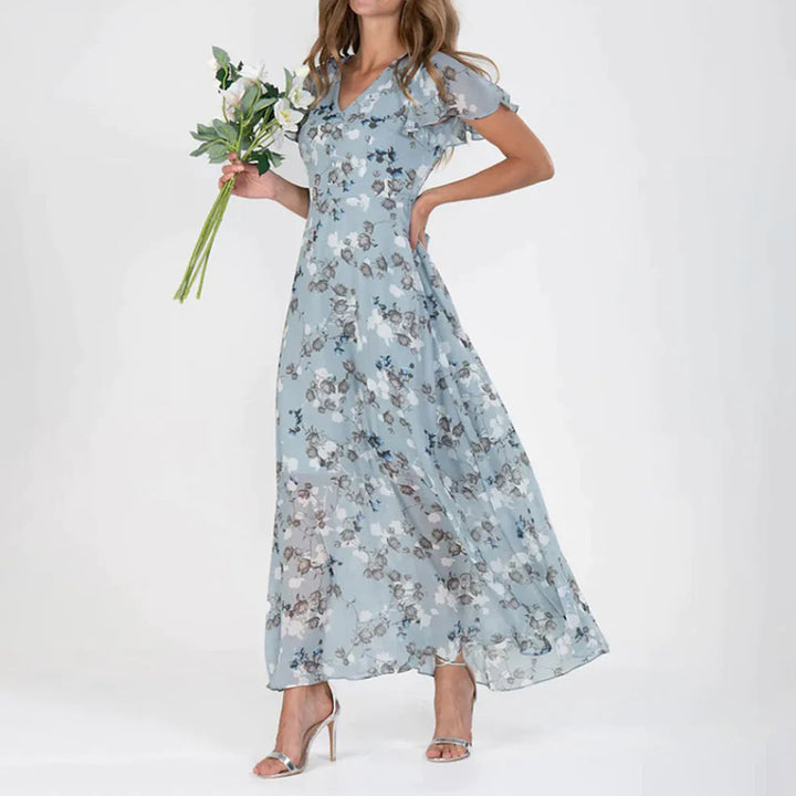 Vrouw in lange blauwe bloemenjurk met korte mouwen, houdt een boeket bloemen vast. Elegante damesmode, zomerjurk, casual chique stijl.