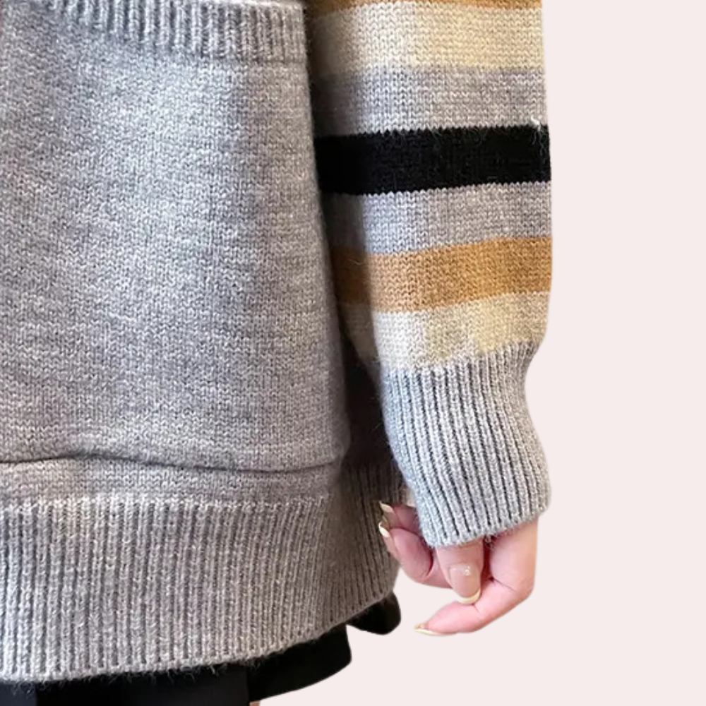 Grijze gebreide trui met gestreepte mouw in beige, zwart en goud. Modieuze dameskleding, herfst-winter collectie, comfortabele pasvorm.