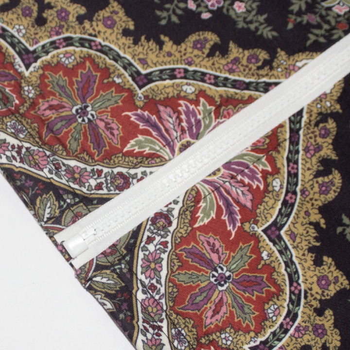 Stoffen met bloemenprint en rits, kleurrijk paisley-patroon, naaiaccessoires, textielontwerp, DIY-projecten, mode- en interieurdecoratie.