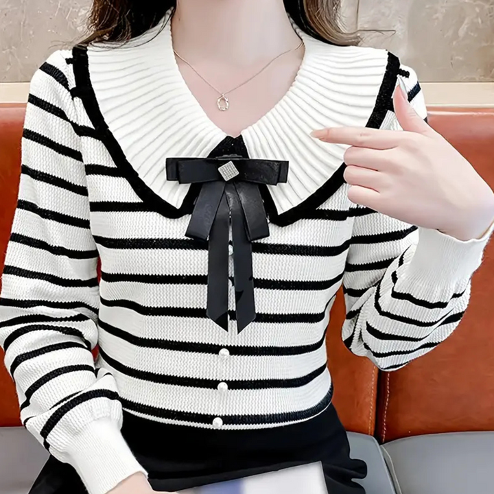 Vrouw in gestreepte trui met grote kraag en zwarte strik, modieuze dameskleding, herfst-winter stijl, casual chique outfit.