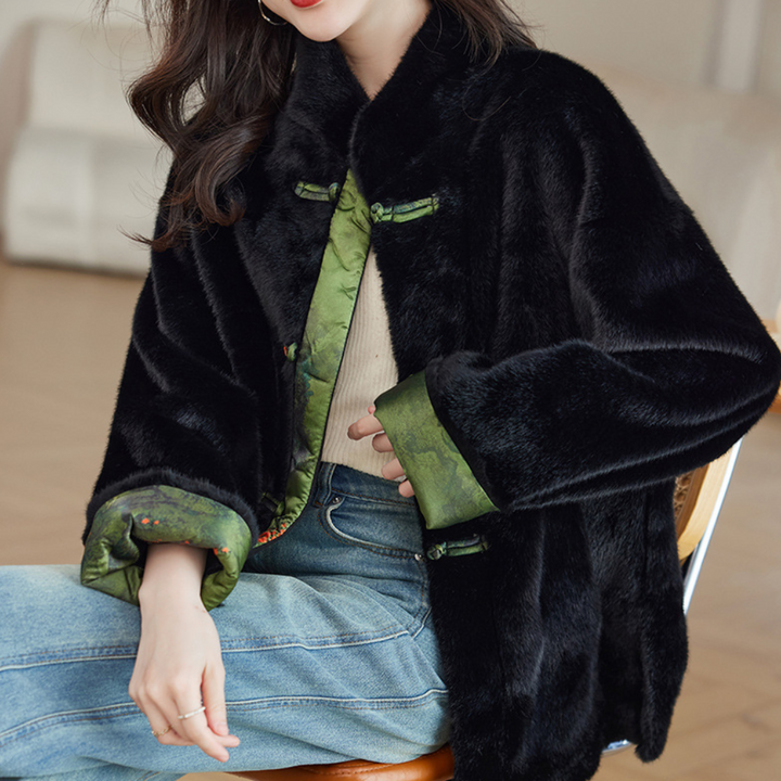 Zwarte faux bontjas met groene voering, gedragen door een zittende vrouw in casual outfit. Modieuze winterkleding, trendy damesmode.