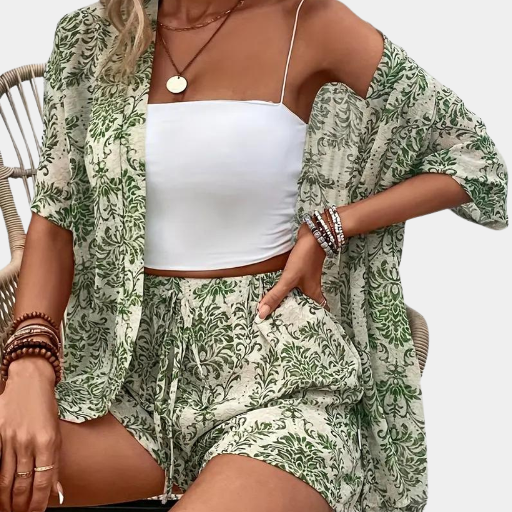 Vrouw draagt groene en witte tweedelige zomerset met bladmotief, bestaande uit een kimono en korte broek. Perfect voor casual zomeroutfits.