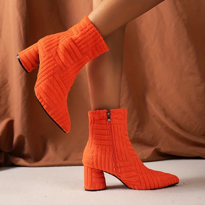 Oranje enkellaarsjes met blokhak en ritssluiting, textuurpatroon. Trendy damesmode, herfst/winter schoenen, opvallende kleur, stijlvol design.