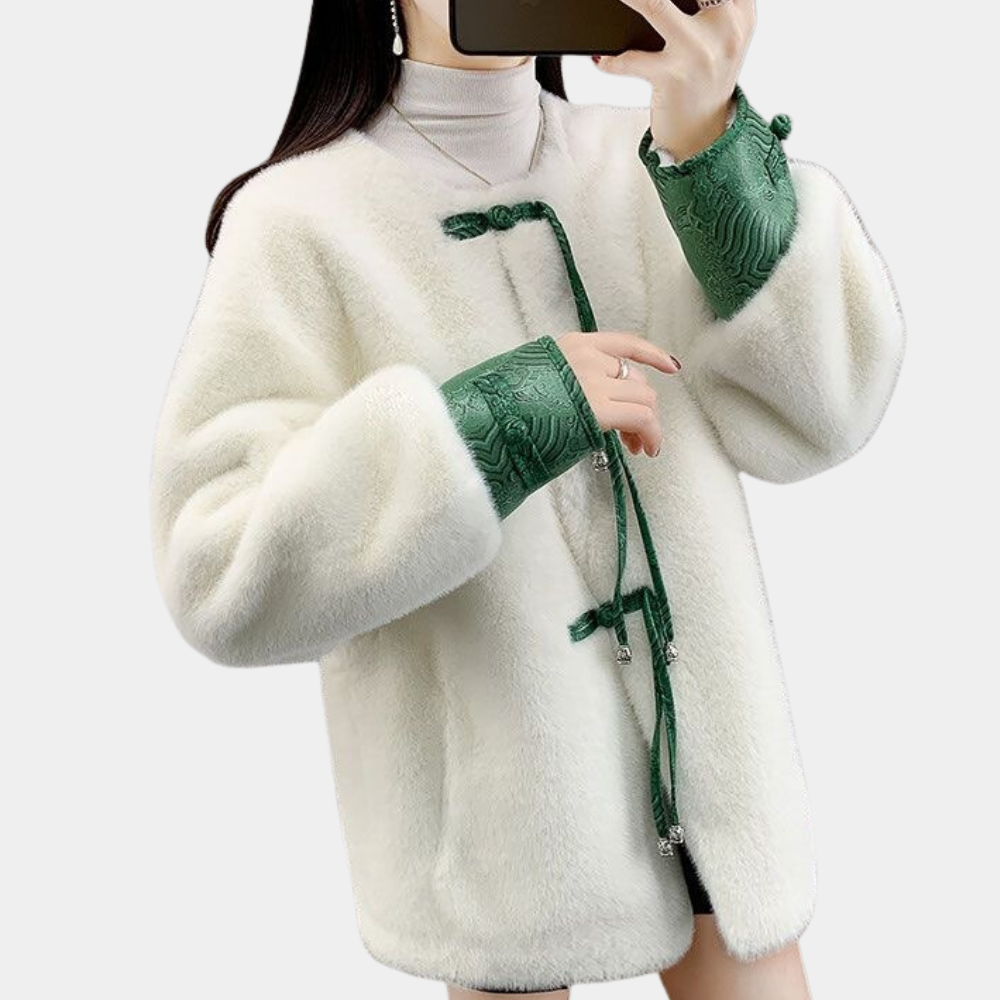 Vrouw in witte faux fur jas met groene geborduurde mouwen, modieuze winterkleding, trendy damesjas, stijlvolle outfit voor koude seizoenen.