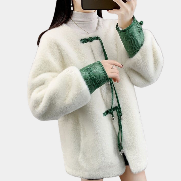Vrouw in witte faux fur jas met groene geborduurde mouwen, modieuze winterkleding, trendy damesjas, stijlvolle outfit voor koude seizoenen.
