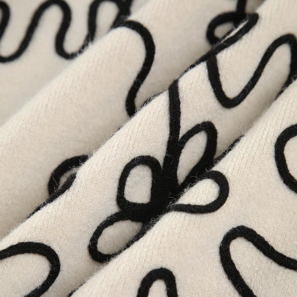 Beige wollen stof met zwarte, golvende lijnenpatroon, close-up. Perfect voor modeontwerp, interieurdecoratie en textielinnovatie.