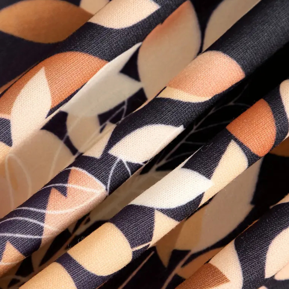 Stof met abstract bladpatroon in zwart, beige en bruin tinten, close-up. Ideaal voor modeontwerp, interieurdecoratie en textieltoepassingen.