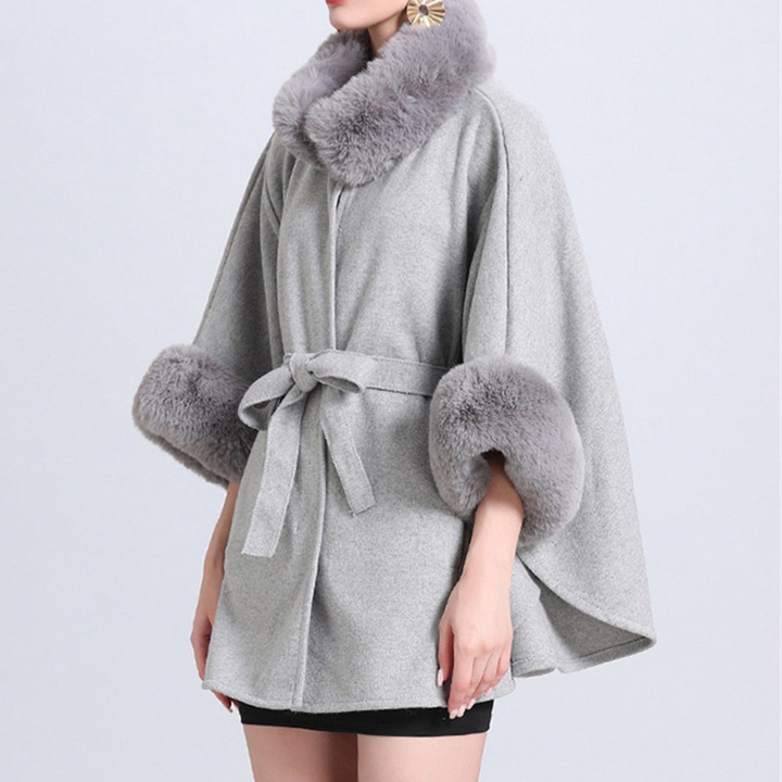 Grijze damescape met kunstbontkraag en manchetten, tailleceintuur, elegante wintermode, stijlvolle warme jas, modieuze dameskleding.