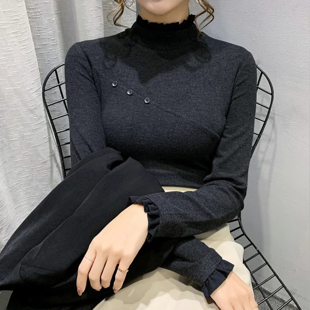Zwarte coltrui met knoopdetails, gedragen door zittende vrouw op metalen stoel, stijlvolle en elegante damesmode, herfst- en winterkleding.