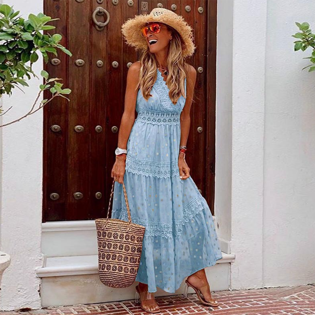 Vrouw in blauwe maxi-jurk met kant, strohoed en zonnebril, poseert voor houten deur. Zomerse mode, boho-stijl, dameskleding.