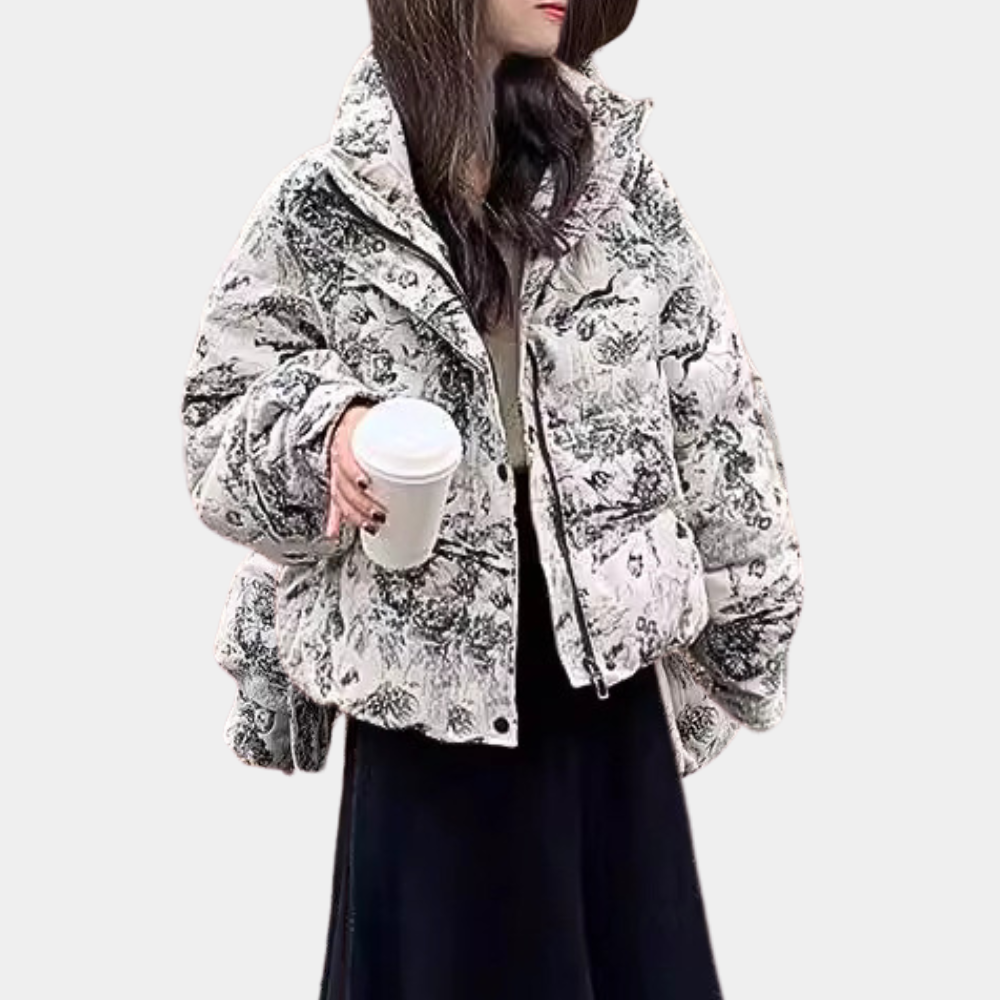Vrouw in modieuze gewatteerde jas met zwart-wit patroon, houdt een koffiebeker vast. Winterkleding, trendy damesjas, casual stijl.