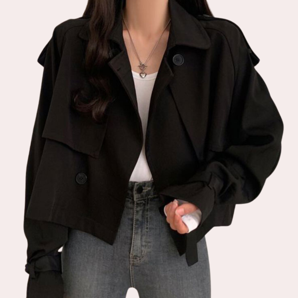Vrouw draagt zwarte oversized jas met knopen, witte top en spijkerbroek. Modieuze dameskleding, herfstjas, casual outfit.