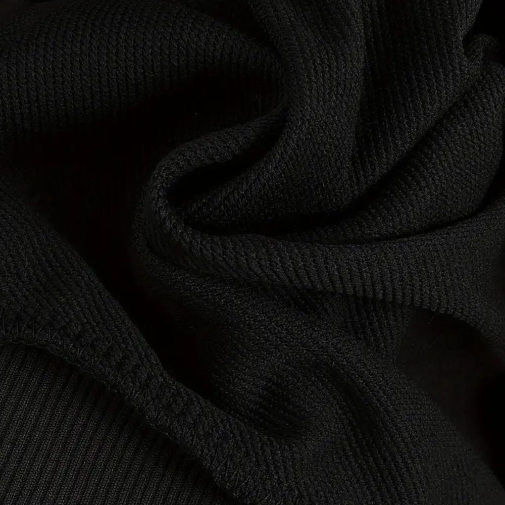 Zwarte ribgebreide stof close-up, textuur van katoenmix, geschikt voor kleding en modeontwerp. Hoogwaardige, duurzame textielmaterialen.