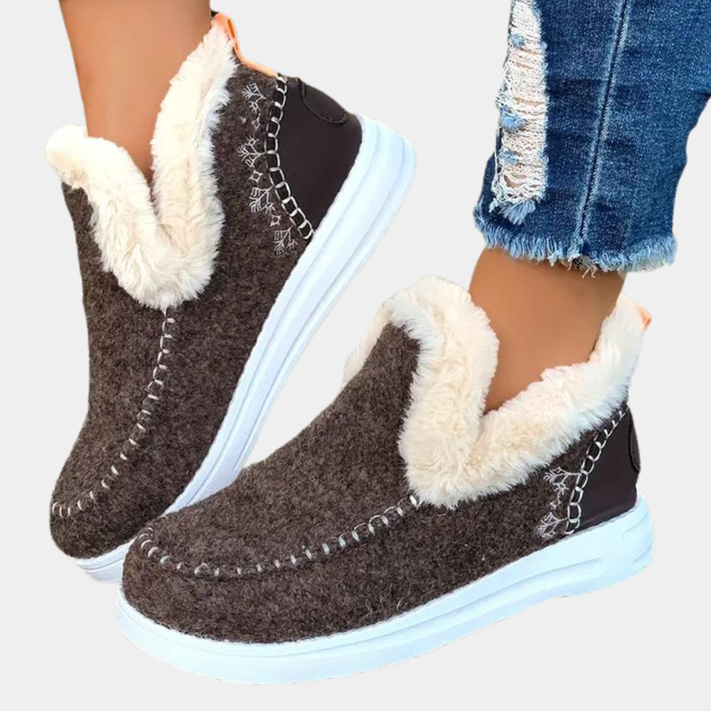Bruine winterlaarzen met witte bontvoering, gestikt patroon en witte zolen, gedragen met gescheurde jeans. Comfortabele en warme dameslaarzen.