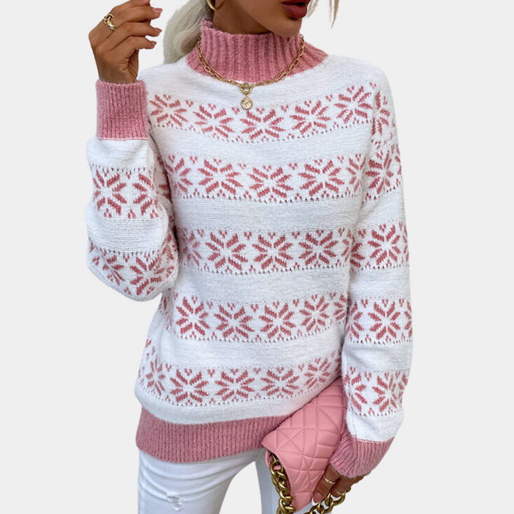 Vrouw in witte en roze gebreide trui met sneeuwvlokpatroon, roze handtas, gouden ketting. Wintermode, stijlvolle dameskleding, trendy outfit.