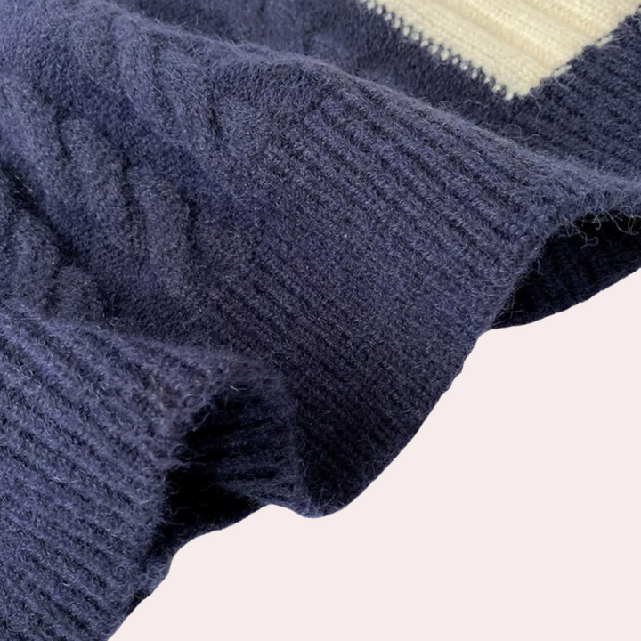 Donkerblauwe gebreide trui met kabelpatroon en witte streep, zachte woltextuur, close-up. Perfect voor wintermode en warme kleding.
