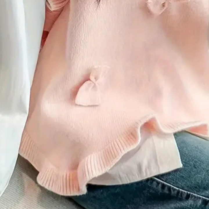 Roze trui met strikdetails, gedragen door persoon in blauwe jeans. Zachte stof, casual mode, trendy dameskleding, comfortabele outfit.