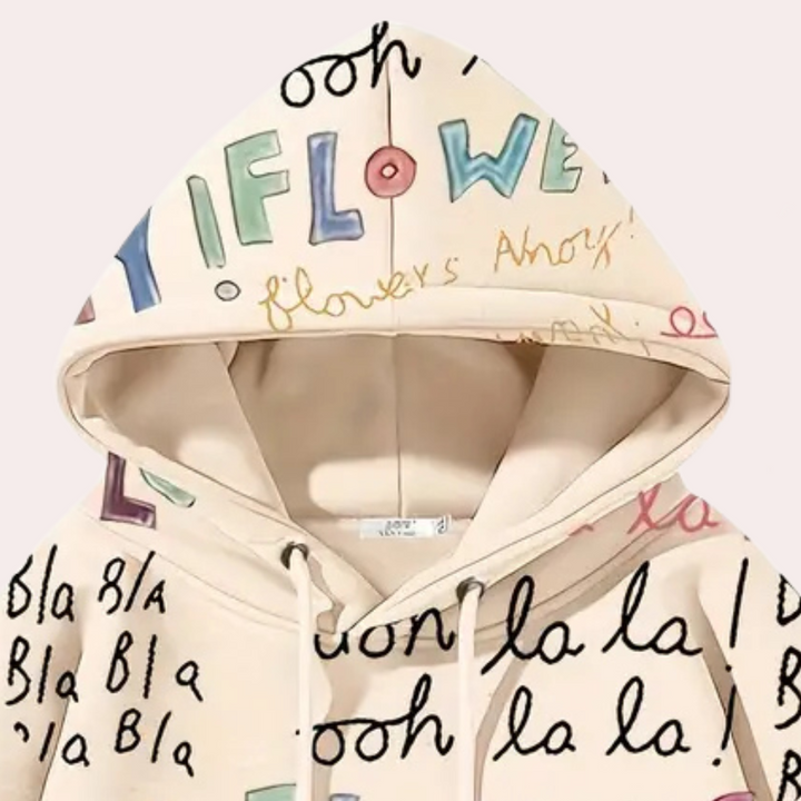 Beige hoodie met kleurrijke, handgeschreven teksten en patronen, zoals "flowers" en "bla bla", op een lichte achtergrond. Trendy streetwear mode.