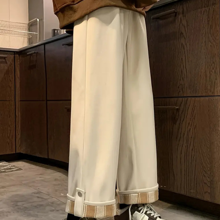 Witte wijde broek met opgerolde zoom, gedragen in moderne keuken. Trendy damesmode, casual stijl, comfortabele pasvorm, bruine kastachtergrond.