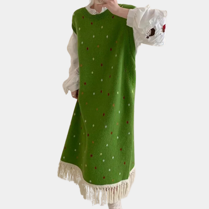 Groene gebreide jurk met kleurrijke stippen en franjes, gedragen over een witte blouse. Trendy damesmode, herfst/winter outfit, casual stijl.