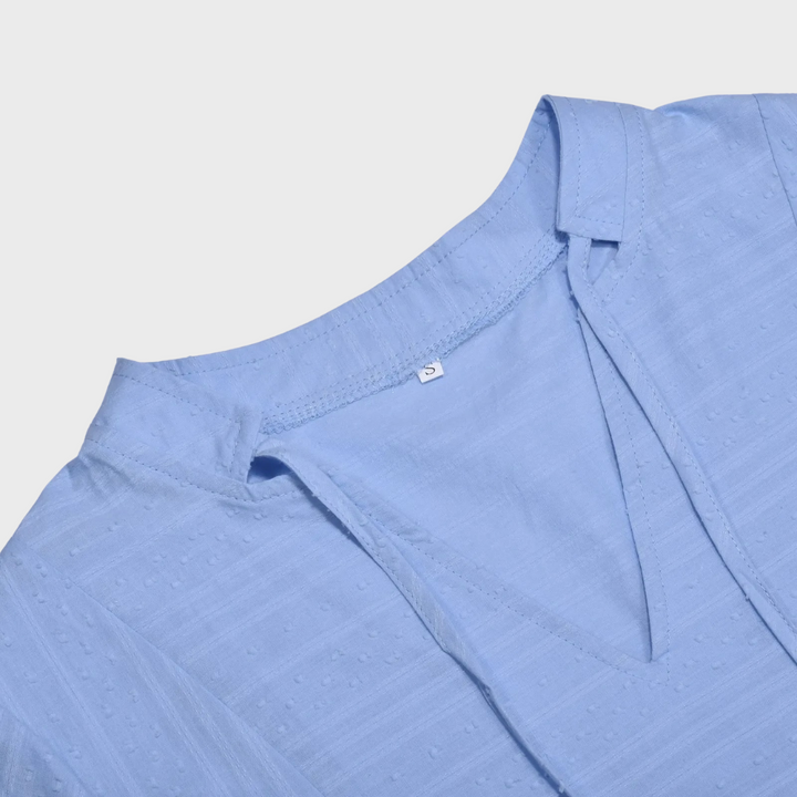 Blauwe dames zomerjurk met V-hals en subtiele textuur, ideaal voor casual en elegante gelegenheden. Perfecte keuze voor zomermode.