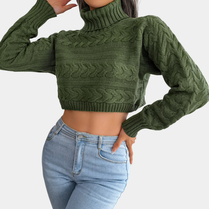 Groene gebreide coltrui crop top met kabelpatroon, gedragen met lichtblauwe high-waisted jeans. Modieuze dameskleding, herfst-winter stijl.