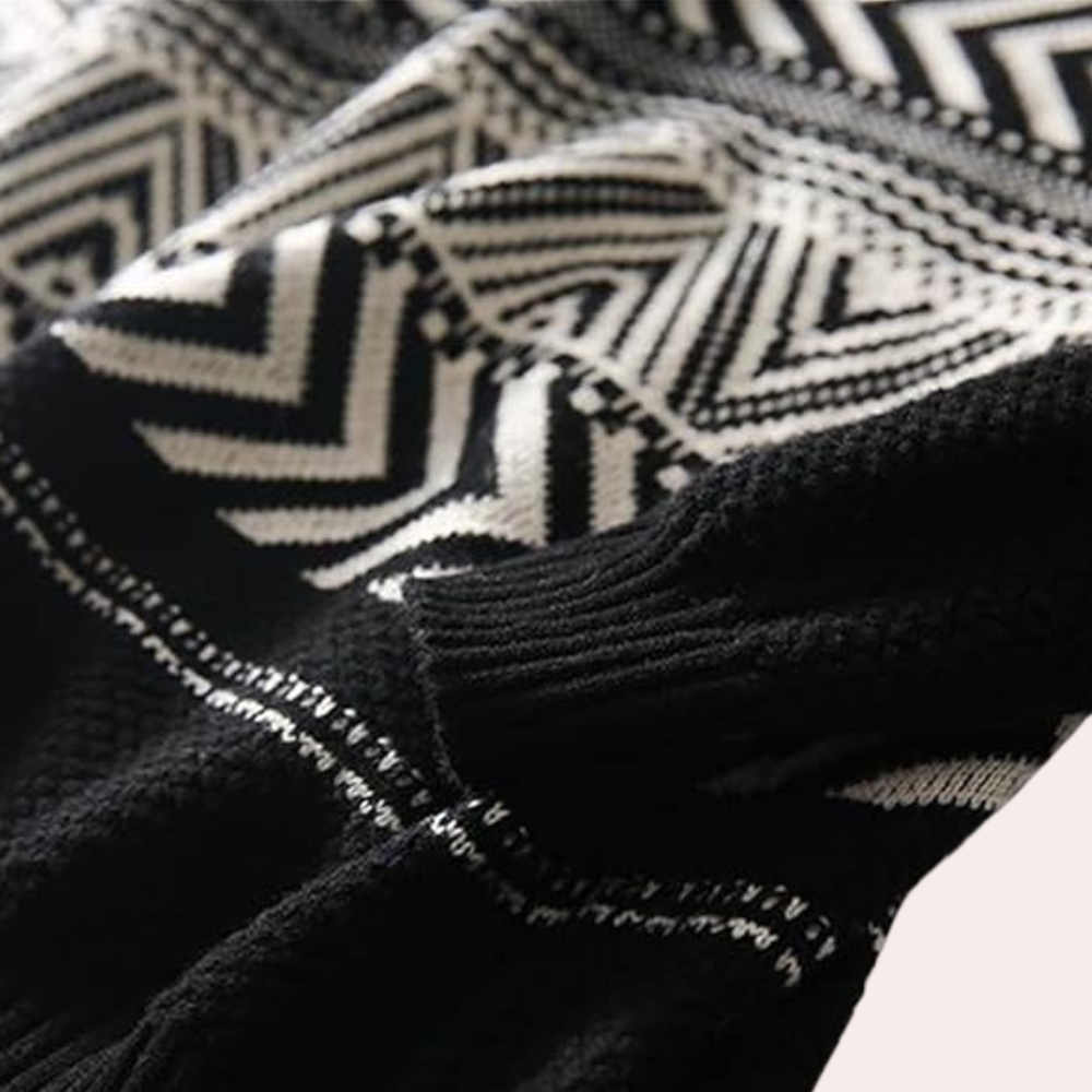 Zwart-witte gebreide trui met geometrisch zigzagpatroon, close-up. Modieuze winterkleding, warme stof, trendy design.