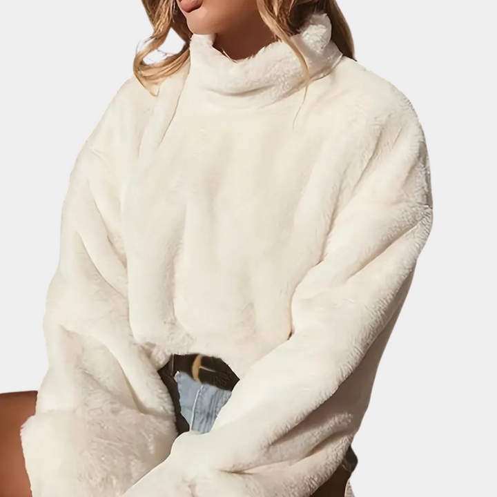 Vrouw draagt een witte, oversized teddy trui met col, gecombineerd met een spijkerbroek. Modieuze winterkleding, comfortabel en stijlvol.