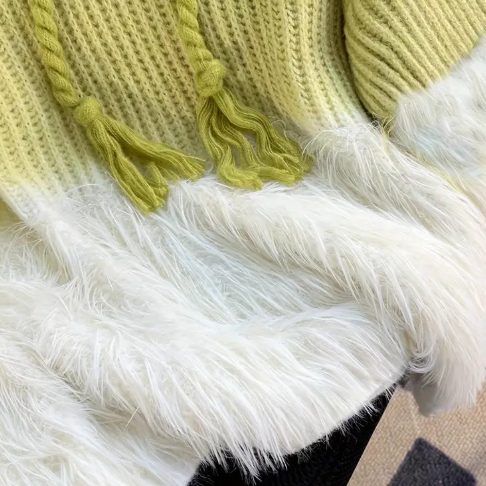 Groene gebreide trui met witte, pluizige bontkraag, close-up. Modieuze winterkleding, zachte textuur, trendy damesmode.