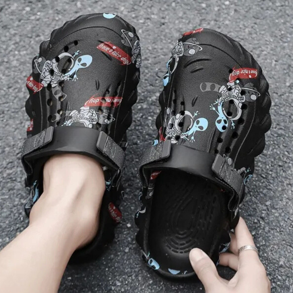 Zwarte klompen met cartoon alien print, verstelbare band en antislip zool, ideaal voor casual gebruik en comfort. Perfect voor zomer en strand.