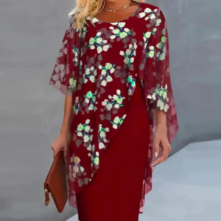 Elegante damesjurk met bloemenprint, rode basis, doorschijnende cape, ideaal voor lente en zomer. Perfect voor modieuze gelegenheden.